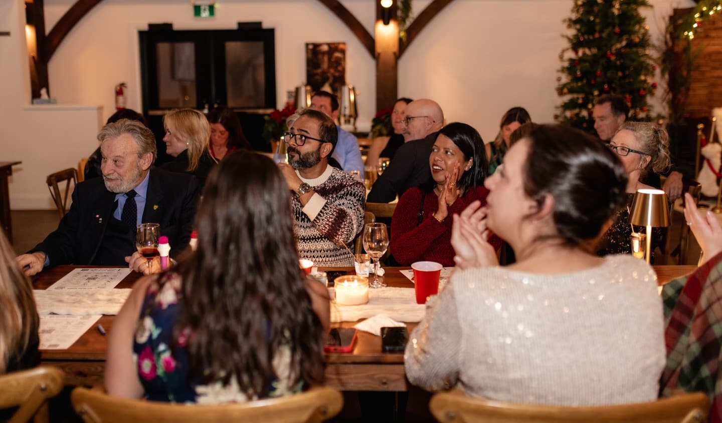 Guests at a corporate holiday party watching the screen and applauding during a round of Music Bingo